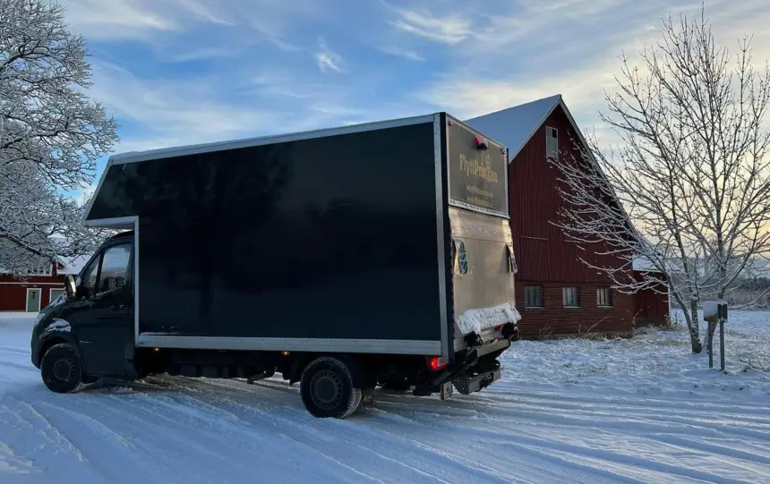 En svart lastbil som används vid flytt i en snöigt landskap.